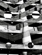 Abstract architectural interior with concrete beams, glass reflections, and circular lights creating a layered geometric pattern.