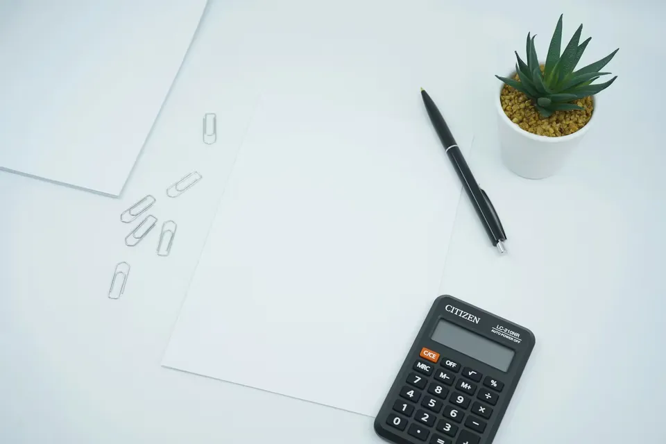 A calculator beside a pen on white printer paper.