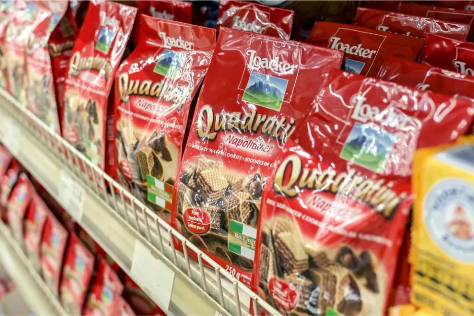 Bags of red Loacker Quadratini Napolitaner chocolate wafer cookies on a supermarket shelf.